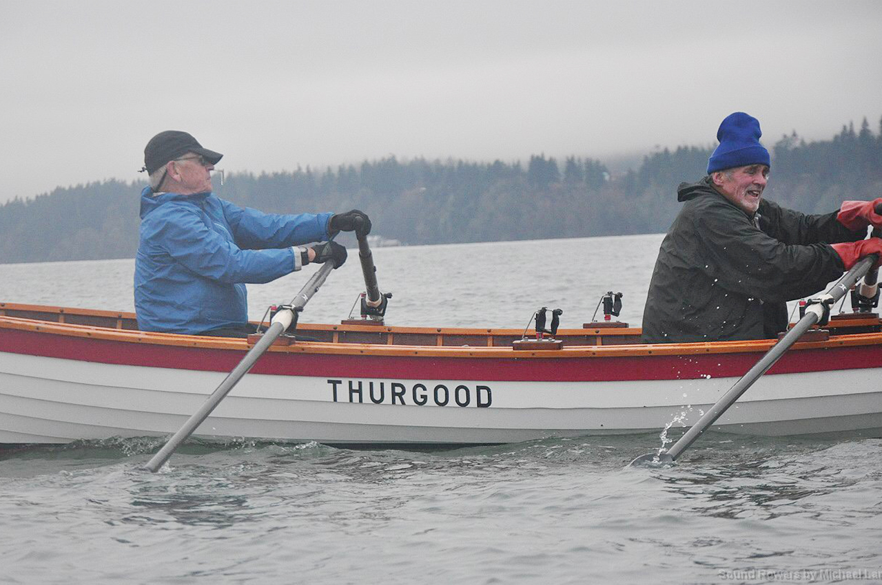 Two stocking-capped rowers pull the Thurgood wherry through LaConner waters